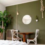 A cozy and modern living space with green walls, natural decor, and comfortable seating.